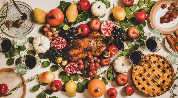 Autumn Thanksgiving, Friendsgiving, family party gathering celebration table setting. Flat-lay of Fall decorated table with roasted duck in fruits, vegetables, cheese board, apple pie and drinks